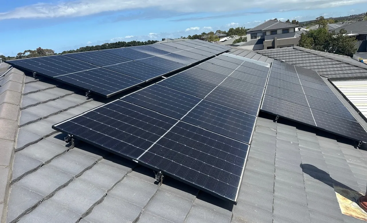 Solar panels installed across a tiled roof with neighbouring houses behind