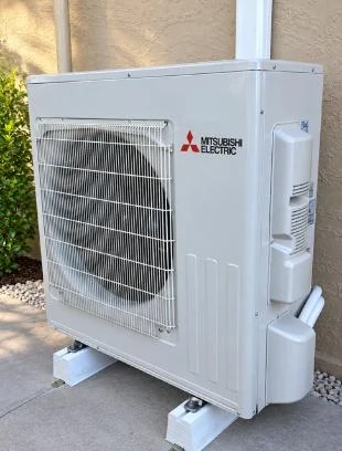 Mitsubishi Electric split system outdoor unit on feet against a rendered wall